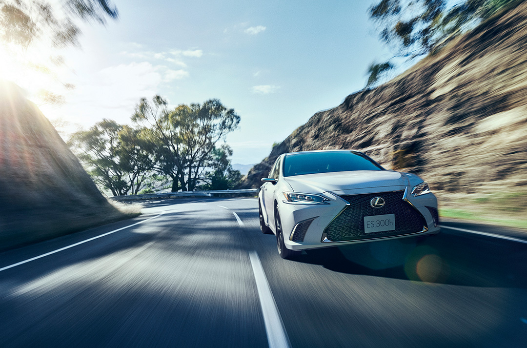 A white ES 250 speeds along a highway road.