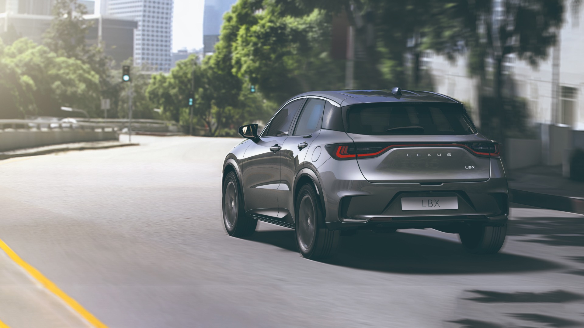 Rear view of a prototype silver Lexus LBX driving on a road.