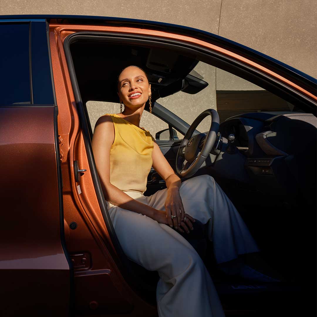 Woman sitting in the driver's seat with the car door open.