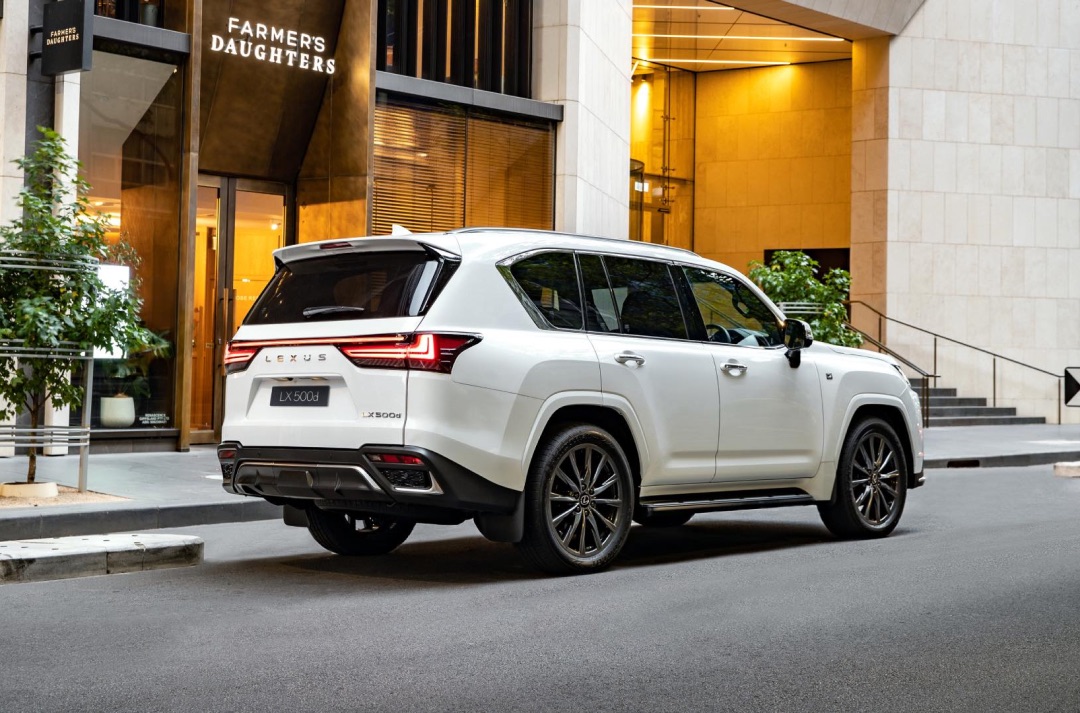 White Lexus LX parked outside a lit up city shop.