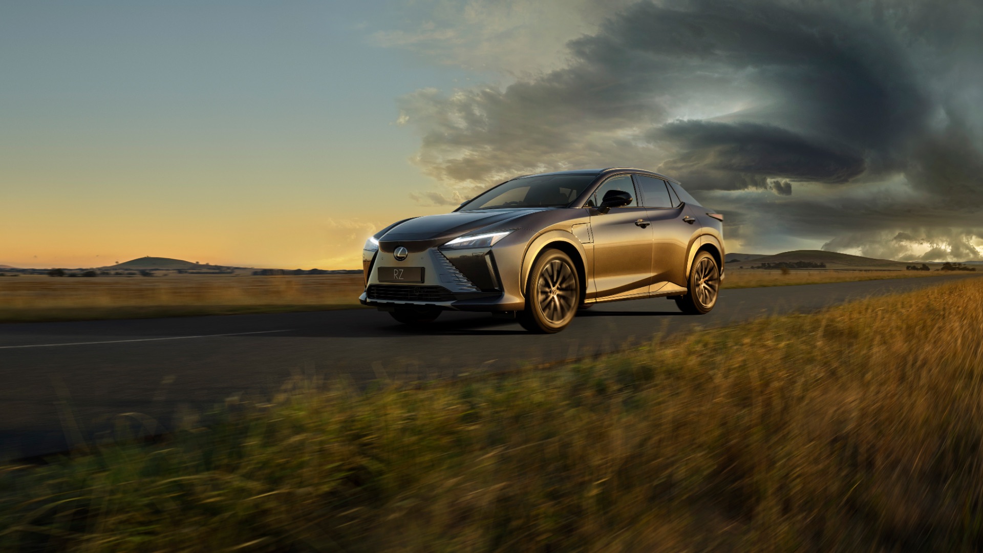 Lexus RZ drives on an Australian countryside road, away from a storm brewing in the far distance.