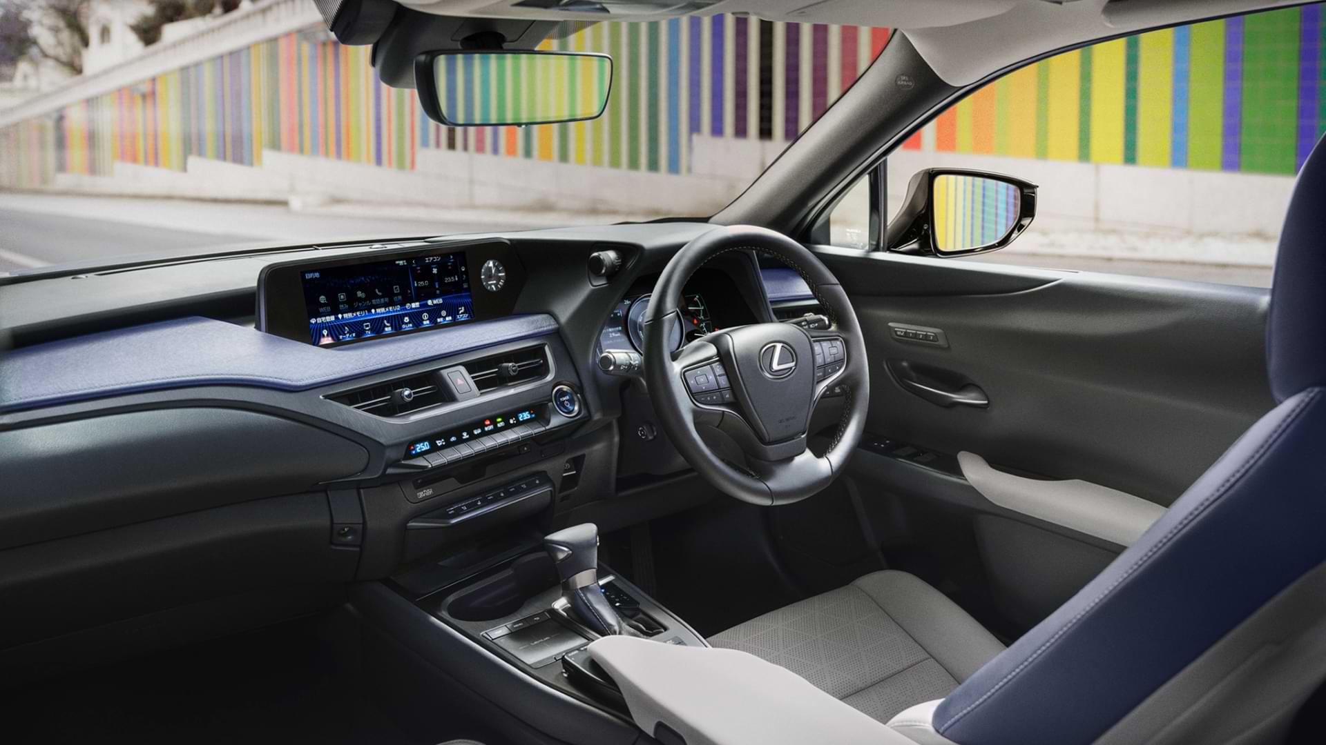 Inside of the 2021 UX, with blue and white leather seats. A rainbow coloured wall is seen as a background.