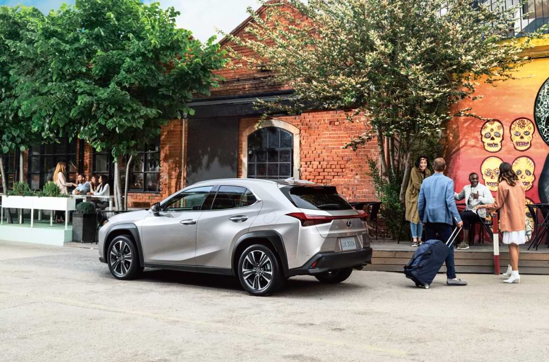 Side view of a car outside, with a few people next to it.