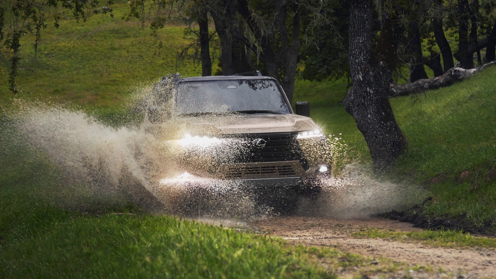Lexus GX is largely covered by splash as it drives through muddy water