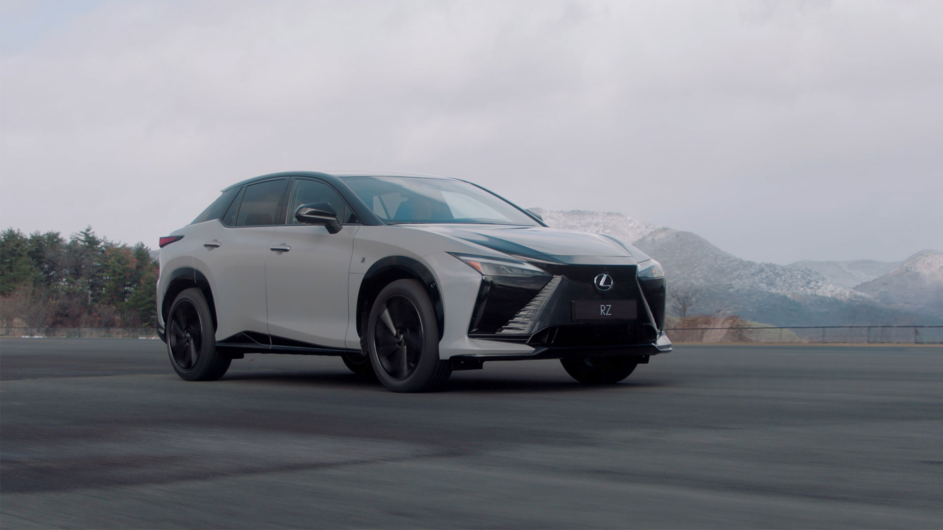 Lexus RZ 550e F Sport driving on a road against a mountainous background