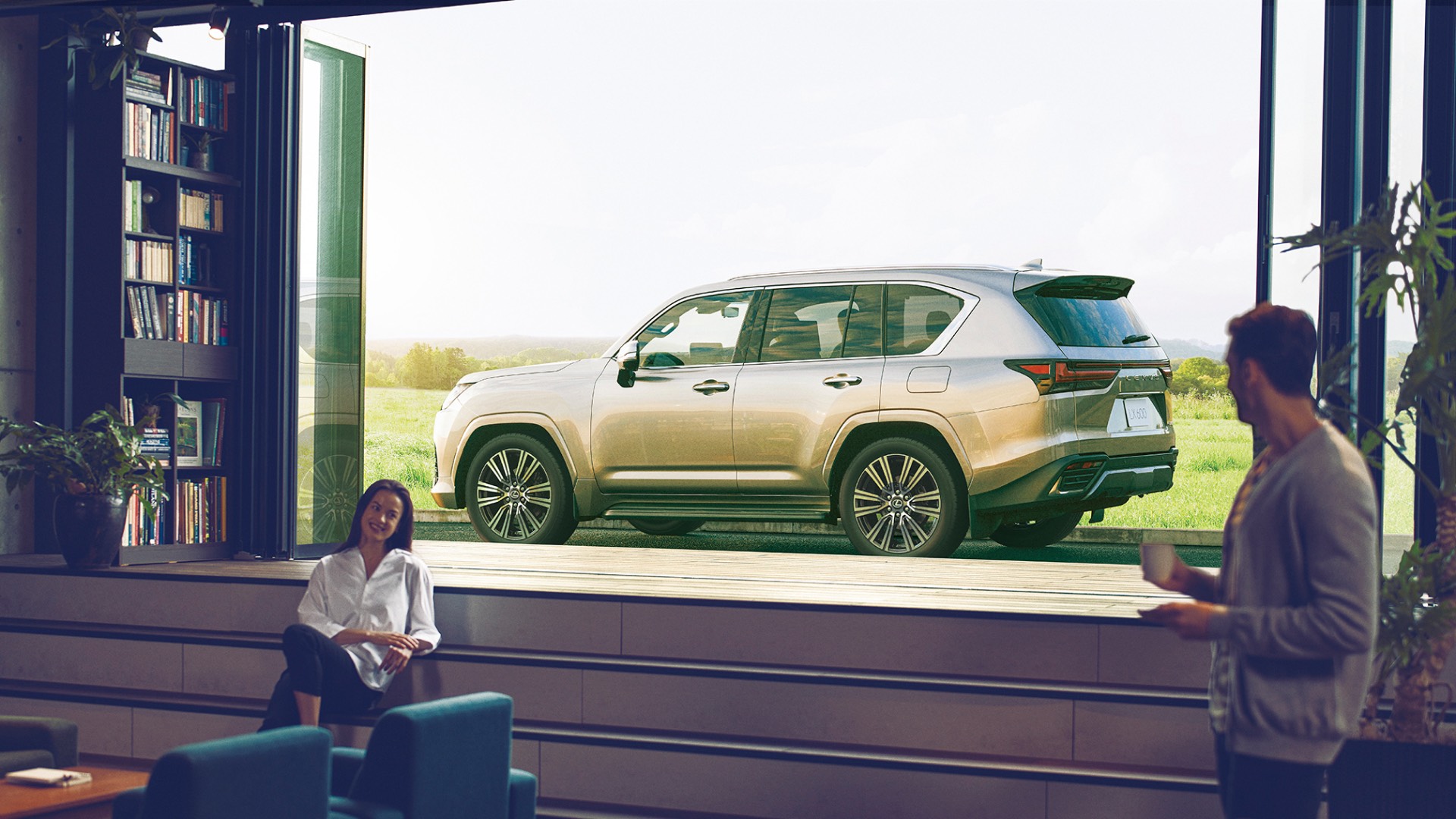 A woman lounges on the couch inside a house, smiling at a man. The LX 600 is in the background outside the house.