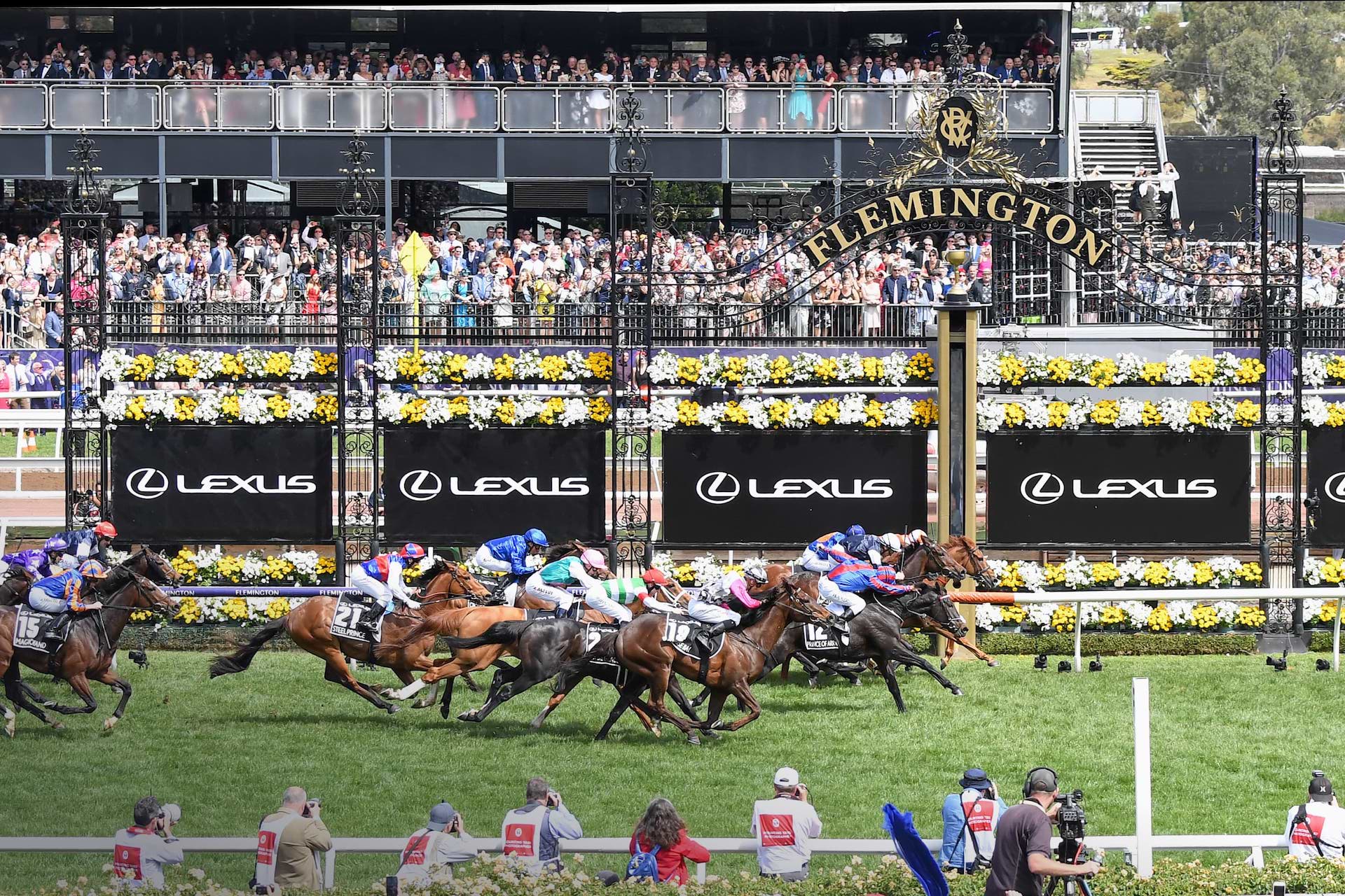 Racehorses sprint toward the finish line at Flemington Racecourse during the Lexus Melbourne Cup as crowds watch.